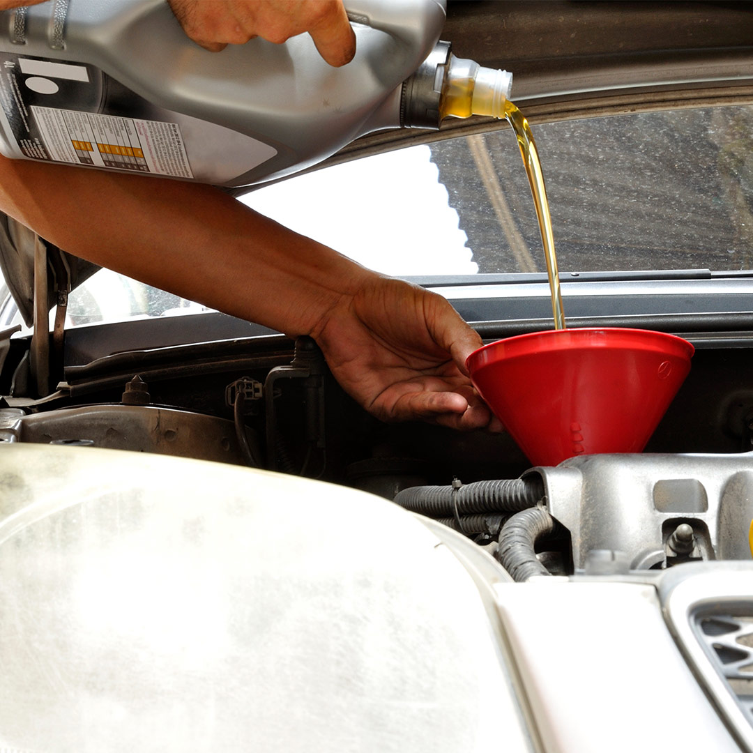 Man pouring oil into a funnel in a car
