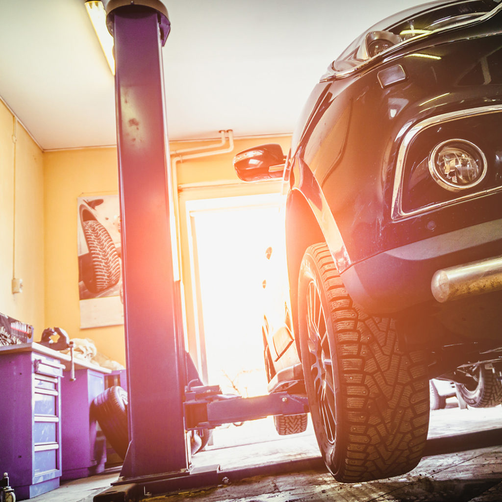 Image of a car on a lift at an auto repair shop having transmission service done.